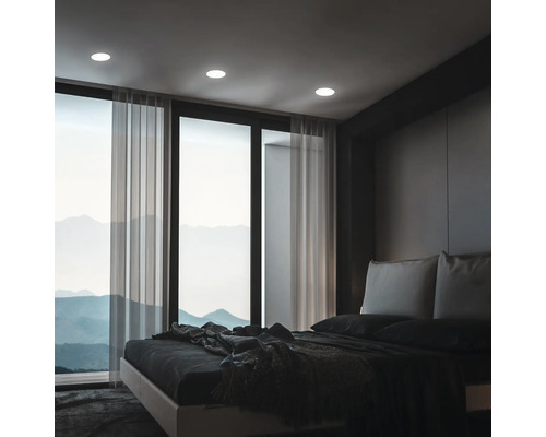 Chambre à coucher avec plafonniers, lit et vue sur la montagne par les fenêtres.