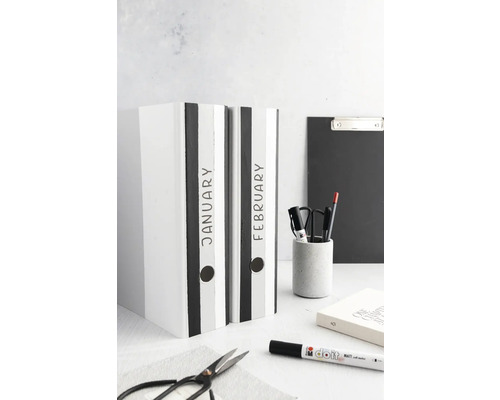 Zwei Ordner mit den Aufschriften Januar und Februar stehen auf einem Tisch.