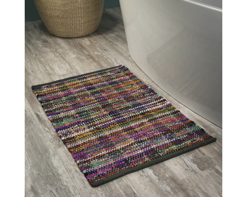 Mehrfarbiger Badteppich neben einer Badewanne auf einem Holzboden