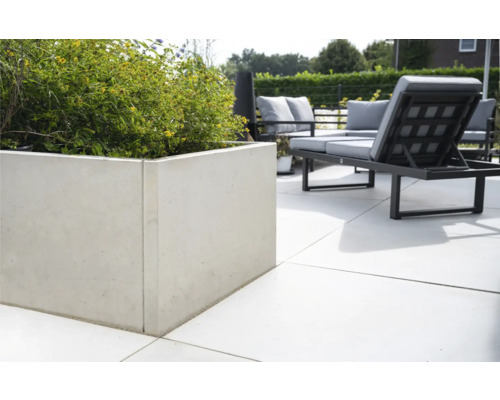 Quadratischer Betonblumenkasten mit Pflanzen und Gartenmöbeln auf der Terrasse.