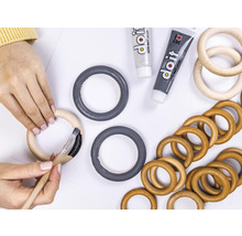 "Eine Person bemalt einen Holzring mit einem Pinsel