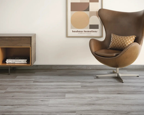 Salon avec sol en vinyle gris, fauteuil, commode et peinture murale