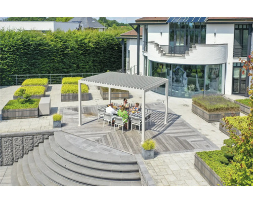 Une famille est assise sous un toit de terrasse sur une terrasse en bois dans un jardin.