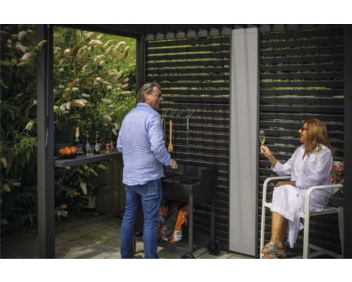 Scène de garden-party avec barbecue sous un toit de terrasse avec un mur à lamelles