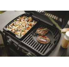 Gril à gaz avec poêle à légumes et deux steaks sur la grille