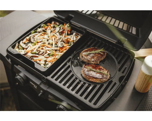 Gril à gaz avec poêle à légumes et deux steaks sur la grille