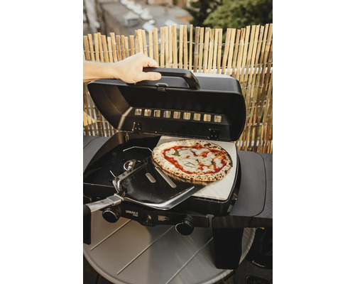 Préparation de pizza sur un barbecue à gaz avec pierre à pizza et pelle à pizza.