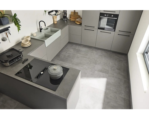 Cuisine lumineuse avec armoires encastrées, évier, plaque de cuisson et carrelage.