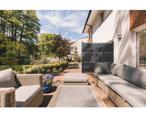 Terrasse avec mobilier en rotin et écran de confidentialité dans le jardin.