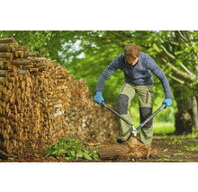 Homme coupant du bois avec une cisaille à branches à côté d''une pile de bois.