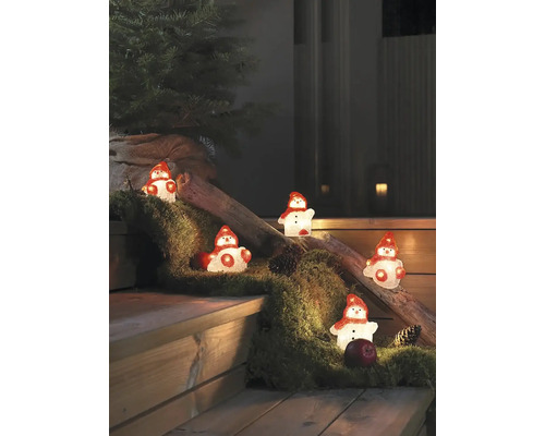 Des figurines décoratives de bonhomme de neige illuminent un escalier en bois avec de la mousse