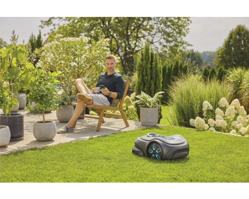 Scène de jardin avec robot tondeuse et homme assis sur une chaise