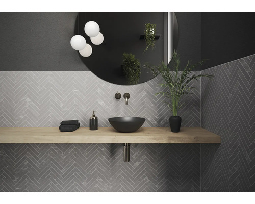 Salle de bains moderne avec lavabo, robinet, miroir et carrelage à chevrons