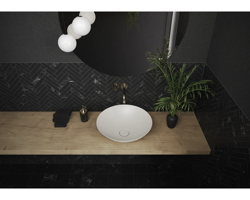 Badezimmer mit Aufsatzwaschbecken, Spiegel, Armatur und Pflanze auf einer Holzplatte.