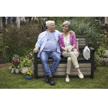 Un couple est assis sur un banc de jardin avec espace de rangement et profite du temps passé dans le jardin.