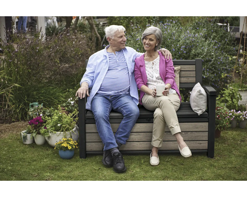 Un couple est assis sur un banc de jardin avec espace de rangement et profite du temps passé dans le jardin.