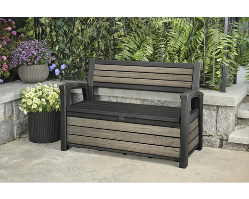 Banc de jardin avec espace de rangement devant des plantes vertes