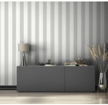 Salon avec papier peint rayé, commode, lampe et décoration