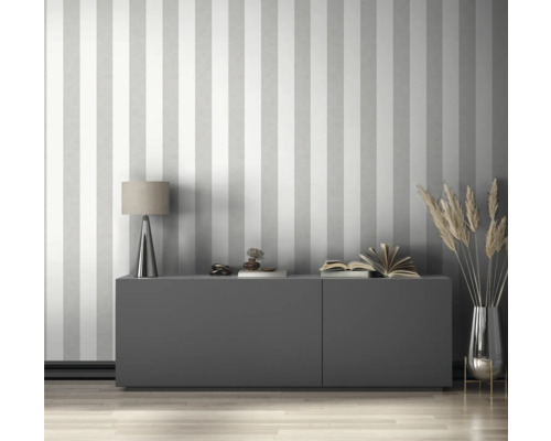 Salon avec papier peint rayé, commode, lampe et décoration