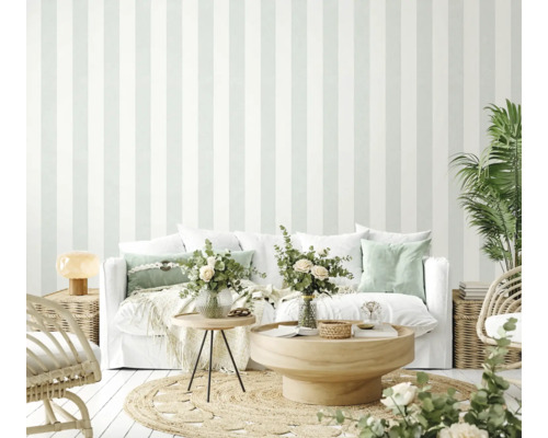 Helles Wohnzimmer mit gestreifter Tapete, Sofa, Tisch und Pflanzen für eine freundliche Atmosphäre.