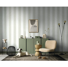 Salon avec papier peint rayé, commode, fauteuil, lampadaire et chien