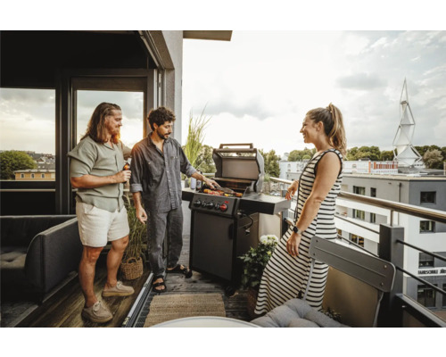 Des personnes font des grillades sur un balcon avec un barbecue à gaz et des meubles de jardin.