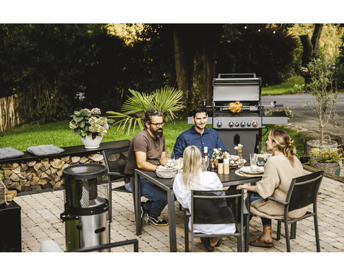 Barbecue en famille ou entre amis dans le jardin avec barbecue, table et chaises.