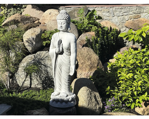 Statue de Bouddha dans le jardin entre les pierres et les plantes