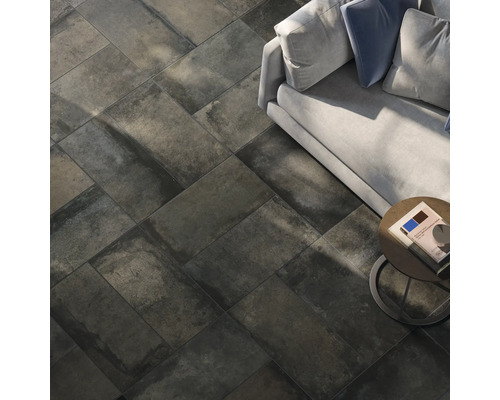 Boden mit dunklen Fliesen in Steinoptik, verlegt im Fischgrätenmuster, Sofa und Beistelltisch