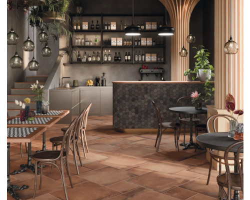 Gastronomiebereich mit Tischen, Stühlen, Bar und terracottafarbenen Bodenfliesen für ein rustikales Ambiente.