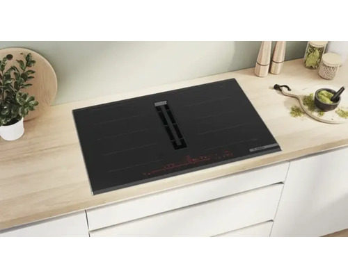 Schwarzes Kochfeld mit integriertem Dunstabzug auf einer Küchenarbeitsplatte.