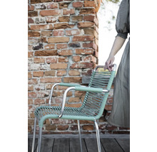 Chaise de jardin avec accoudoirs et assise tressée devant un mur de briques