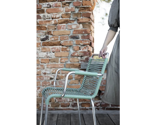 Chaise de jardin avec accoudoirs et assise tressée devant un mur de briques