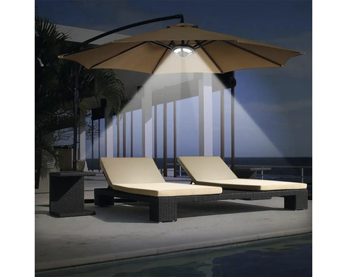 Szene mit zwei Liegestühlen unter einem beleuchteten Sonnenschirm für den Außenbereich