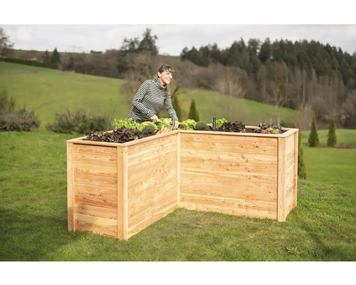 Jardinière en bois dans le jardin avec une femme qui jardine