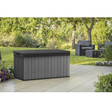 Graue Gartenbox aus Kunststoff auf einer Terrasse mit Gartenmöbeln im Hintergrund