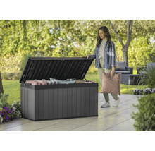 Geöffnete Gartenbox aus Kunststoff mit Kissen und einer Frau im Garten