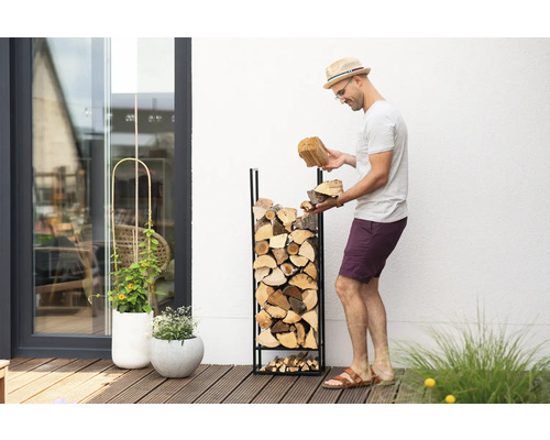 Homme remplissant un range-bûches avec des bûches dans le jardin