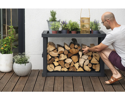 Étagère à bois avec bois et éléments décoratifs à l''extérieur, une personne remplit l''étagère