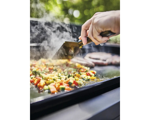 Légumes et viande sur une plaque de cuisson avec une spatule