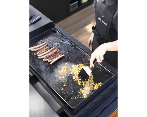 Plancha avec des saucisses et des légumes en préparation