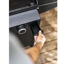 Une personne ouvre le bac de récupération des graisses d''un barbecue.