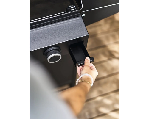 Une personne ouvre le bac de récupération des graisses d''un barbecue.