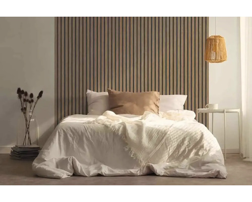 Chambre à coucher avec lit devant un revêtement mural à lattes de bois, table de chevet et lampe