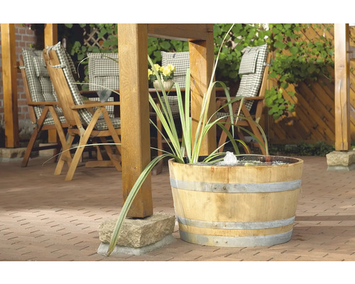 Scène de jardin avec fontaine en tonneau de bois, mobilier de jardin et plantes sur une terrasse
