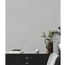 Nahaufnahme einer grauen Vliestapete mit feiner Struktur an einer Wand.