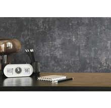 Dekoratives Interieur mit Lampe, Tischuhr, Notizblock und Bleistiften auf einem Tisch vor einer strukturierten Wand