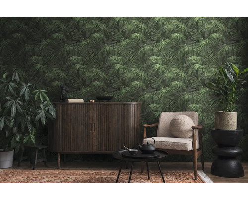 Salon avec meubles foncés, fauteuil, plantes d''intérieur et papier peint feuilles de palmier