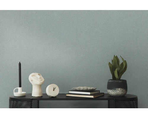 Dekoratives Arrangement mit Kerze, Skulptur, Uhr, Büchern und Zimmerpflanze auf einem Regal