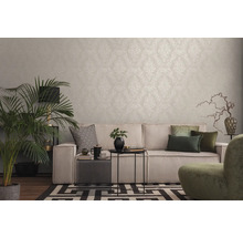 Wohnzimmer mit gemusterter Tapete, Sofa, Zimmerpflanze und dekorativen Elementen für ein gemütliches Ambiente